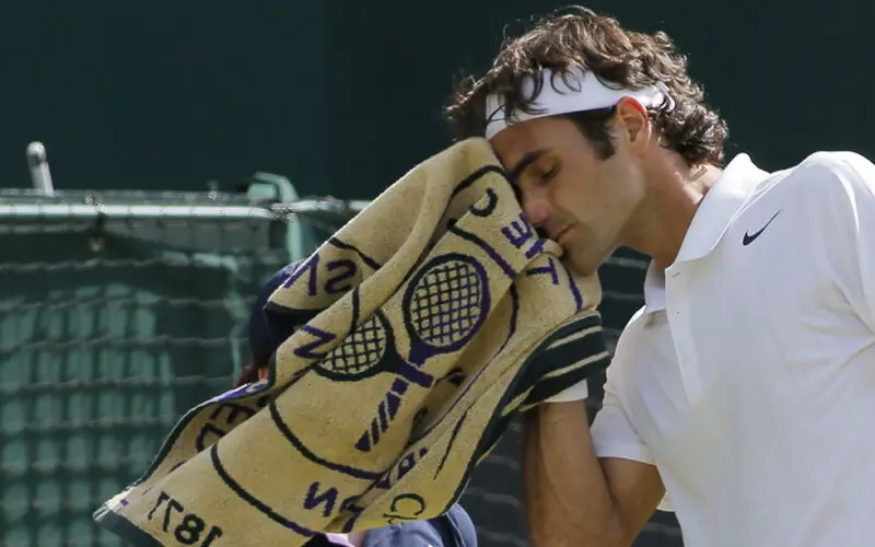 Roger Federer of Switzerland wipes his face with a towel as he plays against Stan Wawrinka of Switzerland during their men's singles quarterfinal match at the All England Lawn Tennis Championships in Wimbledon, London, Wednesday, July 2, 2014. (AP Photo/Pavel Golovkin)