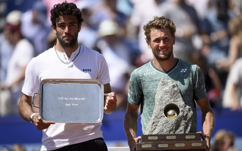 epa10089550 Casper Ruud of Norway, right, takes a pose with the trophy after wining his game against Matteo Berrettini of Italy, left, during the final round game at the Swiss Open tennis tournament in Gstaad, Switzerland, 24 July 2022.  EPA/ANTHONY ANEX