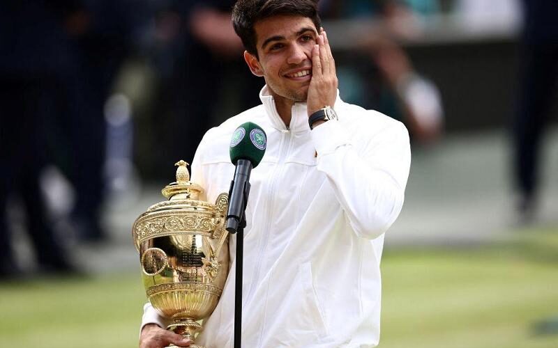 Spain's Carlos Alcaraz holds the winner's trophy as he delivers a speech following his victory against Serbia's Novak Djokovic during their men's singles final tennis match on the fourteenth day of the 2024 Wimbledon Championships at The All England Lawn Tennis and Croquet Club in Wimbledon, southwest London, on July 14, 2024. Defending champion Alcaraz beat seven-time winner Novak Djokovic in a blockbuster final, with Alcaraz winning 6-2, 6-2, 7-6. (Photo by HENRY NICHOLLS / AFP) / RESTRICTED TO EDITORIAL USE (Photo by HENRY NICHOLLS/AFP via Getty Images)